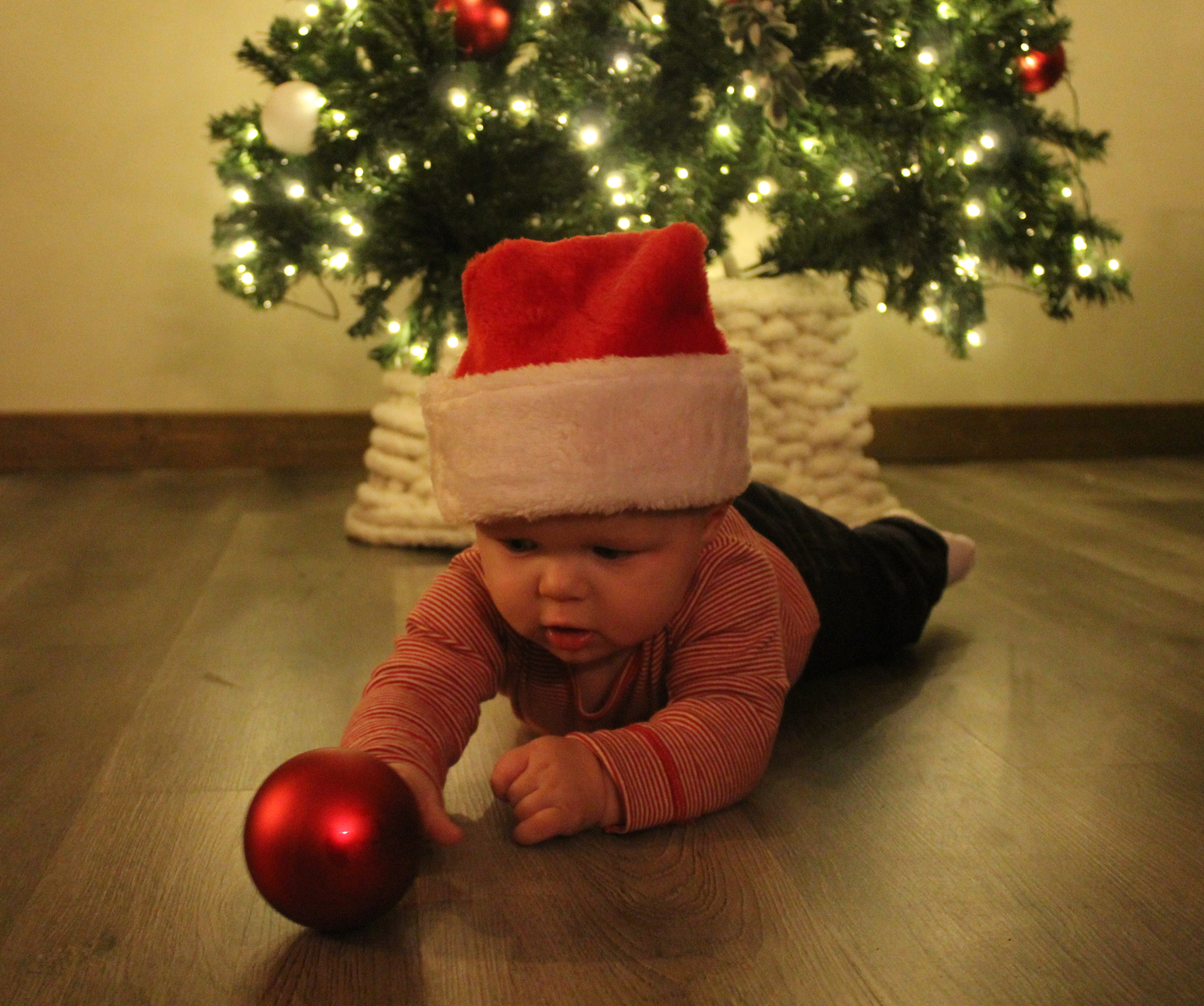 A woman in her wedding dress is sitting on the beach with flowers.