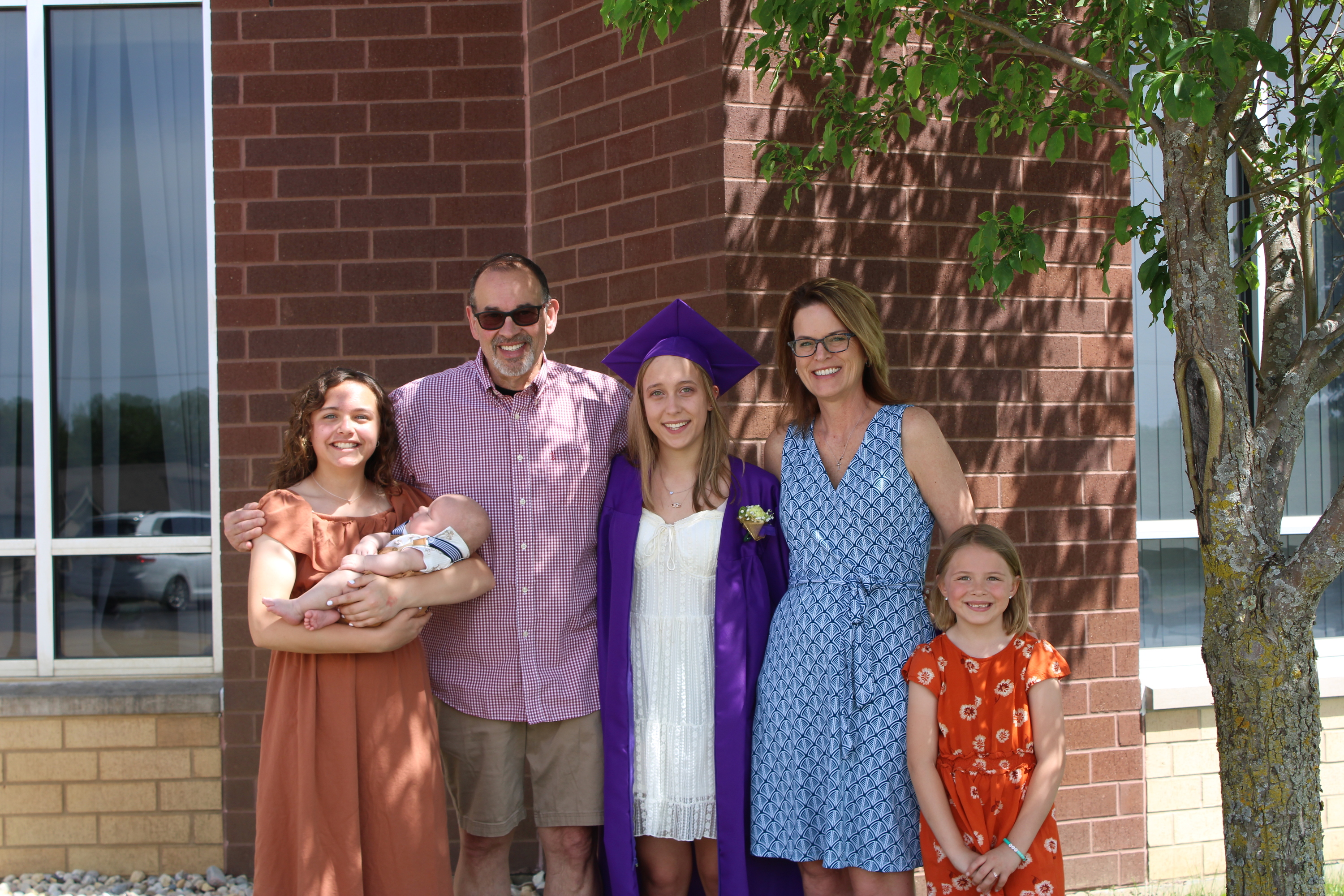 A woman in her wedding dress is sitting on the beach with flowers.