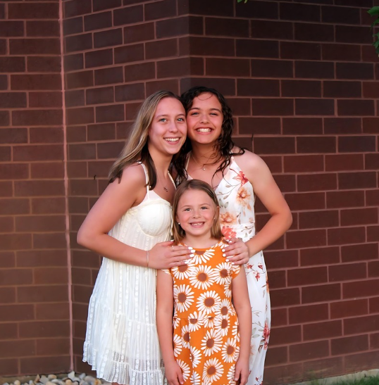 A woman in a wedding dress is standing in front of the sea on the rocks.
